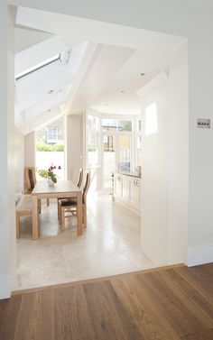 an open floor plan with white walls and wooden furniture in the dining room, looking into the kitchen