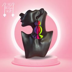 a black mannequin head with colorful earrings on it's face and pink background