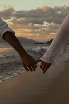 two people holding hands while walking along the beach