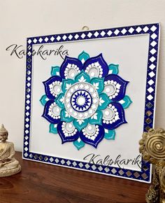 a blue and white card with an intricate design on the front, sitting on a table next to a buddha figurine