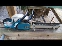 a blue and white chainsaw sitting on top of a wooden bench