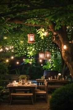 an outdoor dining area is lit up with string lights and lanterns hanging from the trees