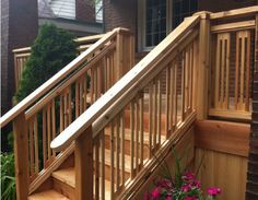 a wooden stair case next to a flower pot with pink flowers on the bottom step