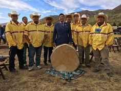 a group of men standing next to each other in front of a large wooden drum