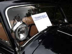 an old black car with a sign on it's headlight and front window