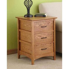 a wooden night stand with three drawers and a lamp on it's end table