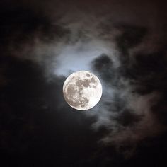 the full moon is seen through some clouds