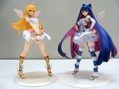 two anime figurines sitting on top of a white table next to each other