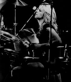 a woman sitting in front of a drum set on top of a drumset,