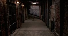 an alley way with brick walls and lights on either side of the walkway, between two buildings