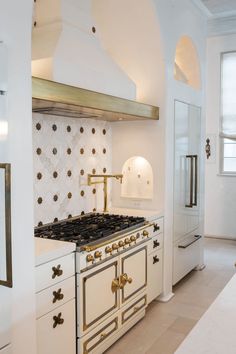 a kitchen with white cabinets and gold accents