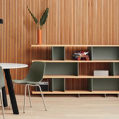 a table and chairs in a room with wood paneling on the wall behind them