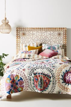 a bed with an intricately designed headboard and quilted bedspread in a white room