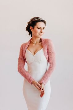 a woman in a white dress and pink cardigan posing for the camera with her hands on her hips