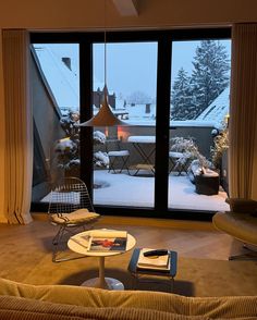 a living room filled with furniture and a large window overlooking the snow covered yard outside