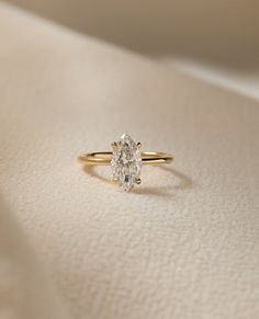 a diamond ring sitting on top of a white cloth covered tablecloth with a gold band