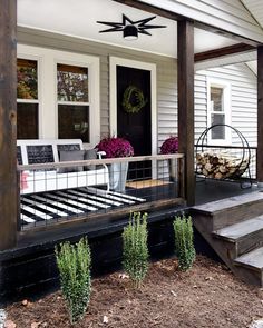 a porch with steps leading up to the front door and flowers in pots on the deck