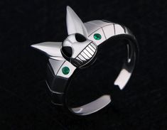 a close up of a ring with an animal design on the front and green eyes