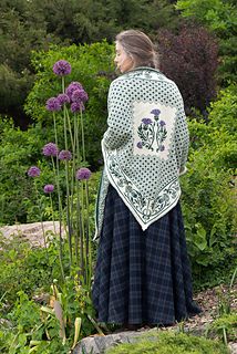 a woman in a long dress standing next to some purple flowers and green plants, with her back turned towards the camera