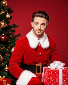 a man dressed as santa clause sitting next to a christmas tree