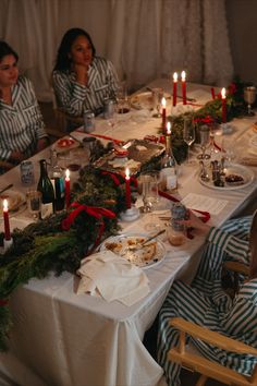 two women sitting at a table with food and candles in front of them on christmas morning