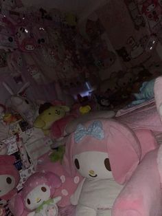 there are many stuffed animals on the bed together and one is wearing a pink bow