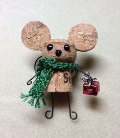 a mouse figurine with a green scarf around it's neck holding a red present