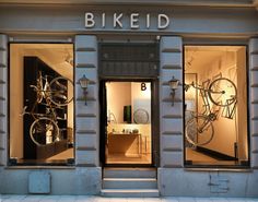 the storefront of a bike shop with bikes in it's windows and lights on