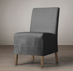 a gray chair sitting on top of a hard wood floor next to a white wall