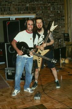 two men standing next to each other with guitars in their hands and headphones on