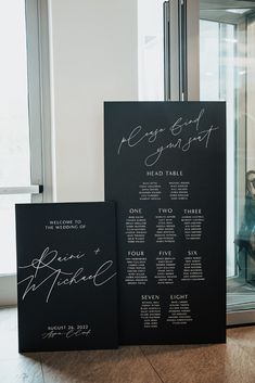 two black menus with white writing on them sitting in front of a glass door