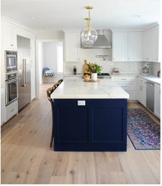 a kitchen with white cabinets and blue island