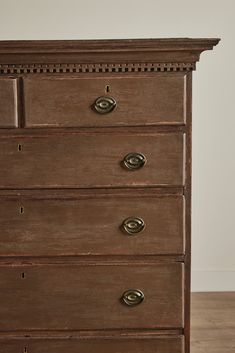 an old wooden dresser with many drawers and knobs on the bottom drawer, in a room