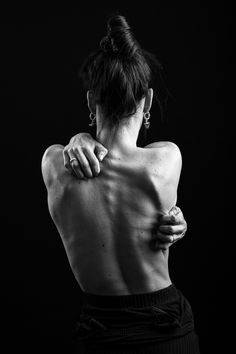 black and white photograph of a woman with her back to the camera, holding her hand on her shoulder