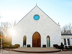 a white brick church with a blue circle in the window and steps leading up to it