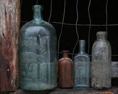 old glass bottles are lined up against a wire fence