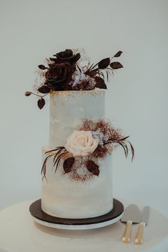 a three tiered cake with white frosting and dried flowers on top, sitting on a table