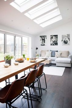 a dining room table with chairs and a couch in front of windows that have skylights on them