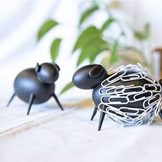 three black sculptures sitting on top of a white sheet next to a potted plant