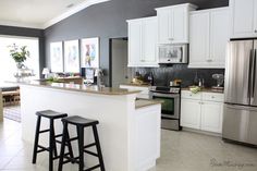 a kitchen with two stools in front of an island and stainless steel refrigerator freezer