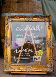 a sign in front of a barrel that says cocktails vodka and bourbon on it