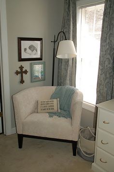 a living room with a chair, lamp and pictures on the wall