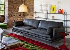 a black leather couch sitting in a living room next to a green and red rug