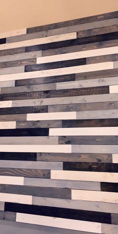 a wooden wall made out of different types of wood planks and painted black, white and gray