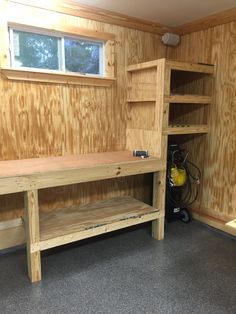 an unfinished workbench in a wood paneled room with gray flooring and walls