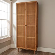 a tall wooden cabinet sitting next to a window in a room with hardwood flooring