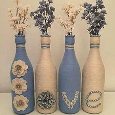 three blue vases with flowers in them sitting on a table next to each other