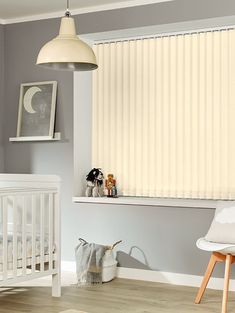 a baby's room with a crib, rocking chair and window covered in blinds