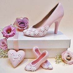 a pair of pink high heels sitting on top of a white box next to flowers