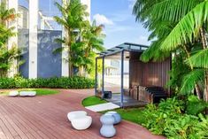 an outdoor area with palm trees, benches and other greenery in front of a building